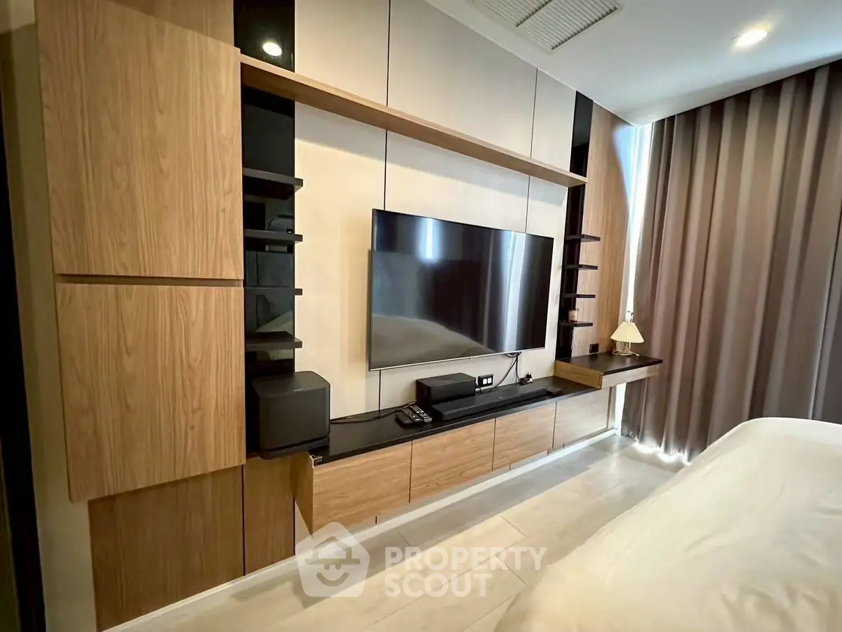 Modern bedroom with sleek wooden cabinetry and large TV setup