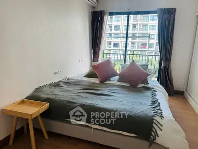 Cozy bedroom with large window and balcony view in modern apartment