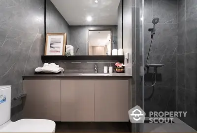 Sleek modern bathroom with dark marble tiles, glass shower, and stylish vanity unit, reflecting a sophisticated urban living space.