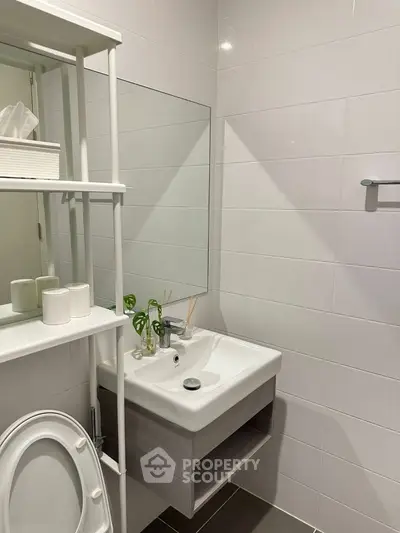Modern bathroom with sleek sink and mirror, featuring white tiles and minimalist decor.