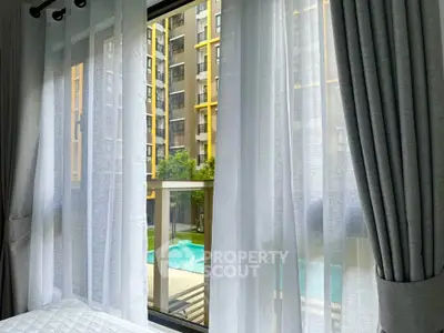 Luxurious apartment view with poolside scenery through elegant curtains.