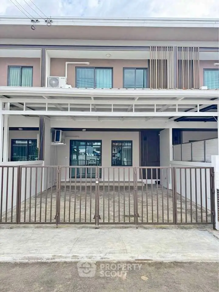 Modern townhouse exterior with gated entrance and large windows.