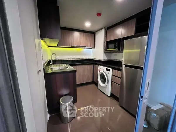 Modern kitchen with sleek cabinetry, stainless steel appliances, and in-unit washer for convenience.