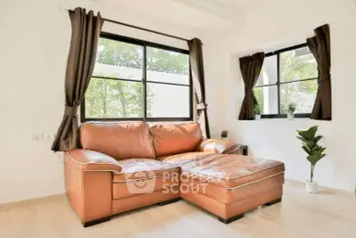 Bright living room with leather sofa and large windows, perfect for relaxation.