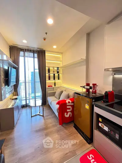 Modern living room with stylish decor and city view, featuring a cozy sofa and sleek kitchen appliances.