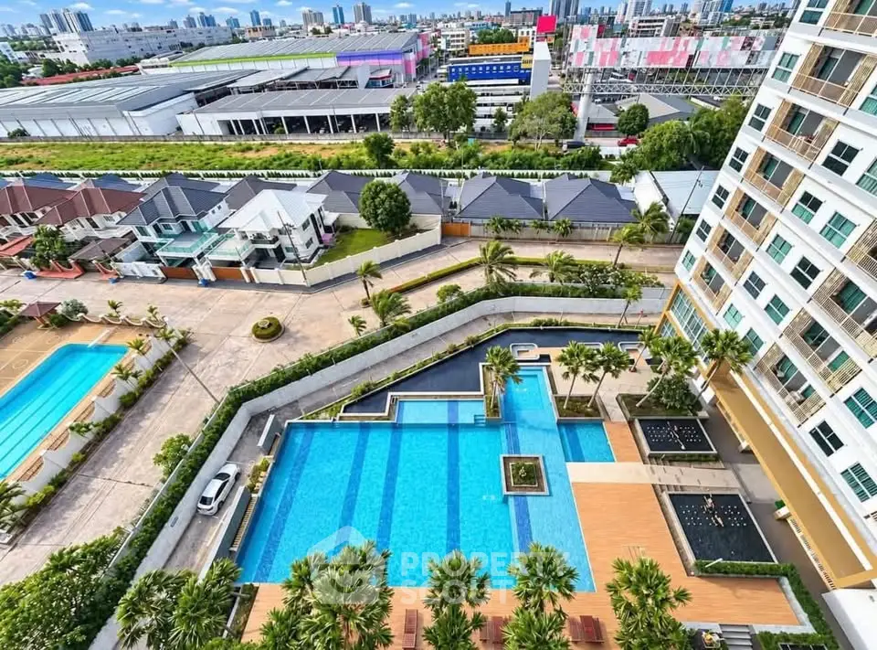 Stunning aerial view of modern apartment complex with luxurious pool and cityscape backdrop.