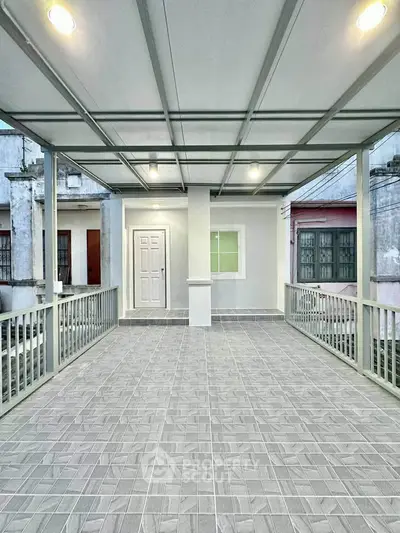 Spacious covered balcony with modern tile flooring and lighting, ideal for outdoor relaxation.