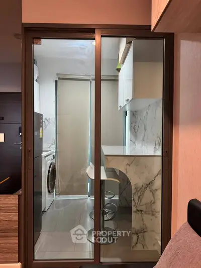 Modern kitchen with marble countertops and washing machine in compact layout