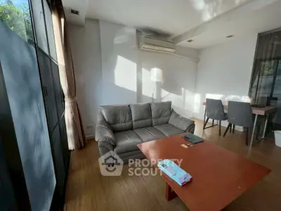 Modern living room with sleek furniture and natural light, featuring a cozy sofa and stylish dining area.
