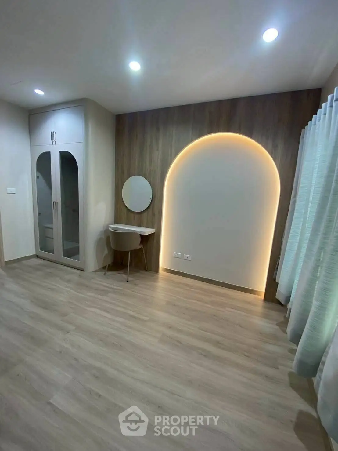 Modern bedroom with stylish lighting and wooden flooring, featuring a built-in wardrobe and a cozy study nook.