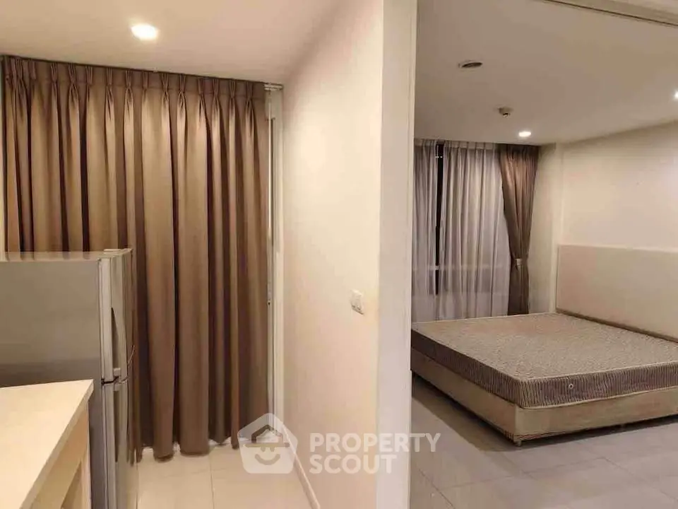 Modern apartment interior with bedroom and kitchen area, featuring sleek design and neutral tones.