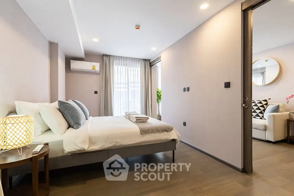 Modern bedroom with cozy decor and adjacent living room in a stylish apartment.