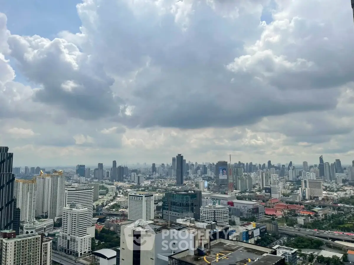 Stunning cityscape view from a high-rise building showcasing urban skyline under dramatic clouds.