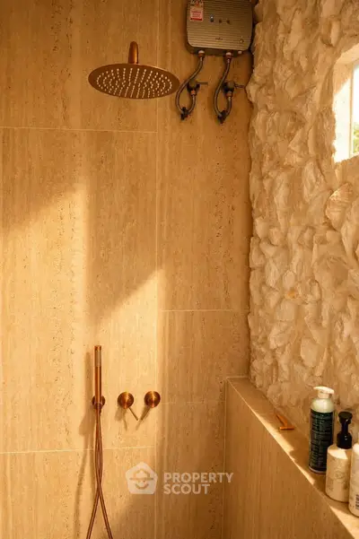 Luxurious stone-tiled bathroom with modern shower fixtures and natural light.