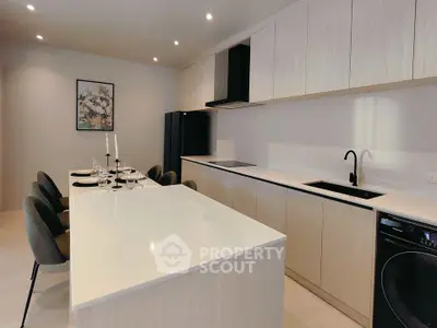 Modern kitchen with sleek design and open layout, featuring a spacious island and elegant dining area.