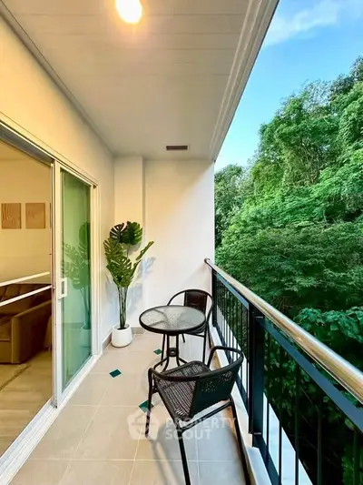 Charming balcony with lush green view, perfect for relaxation and outdoor dining.