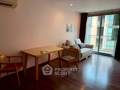 Cozy living room with wooden flooring, modern furniture, and balcony access in a stylish apartment.