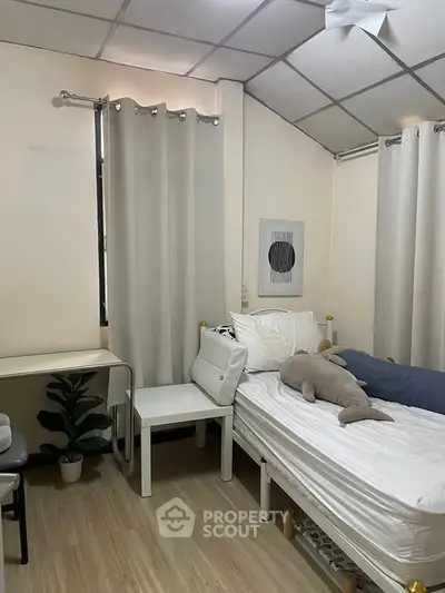 Cozy bedroom with minimalist decor and natural light, featuring a comfortable bed and study area.