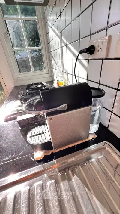 Charming kitchen corner with espresso machine and sunlit window view.