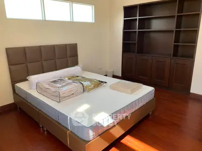 Spacious bedroom with elegant wooden flooring and built-in shelving