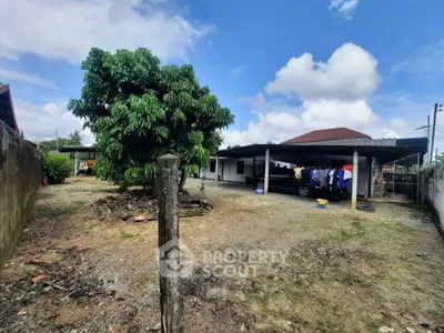 Spacious outdoor area with a large tree and carport in a residential property.