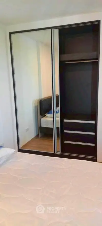 Spacious bedroom with mirrored wardrobe and modern bed frame, perfect for stylish living.