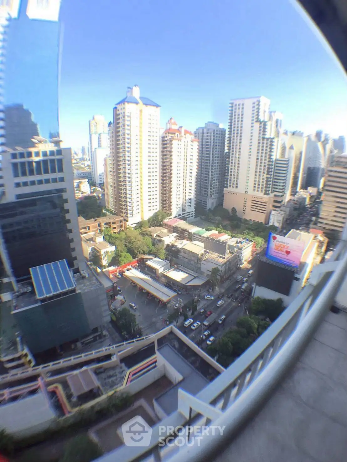 Stunning cityscape view from a high-rise balcony overlooking urban skyline and bustling streets.
