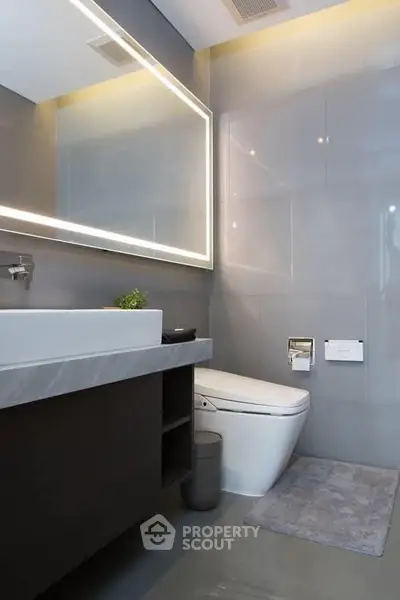 Modern bathroom with sleek design, illuminated mirror, and elegant fixtures.
