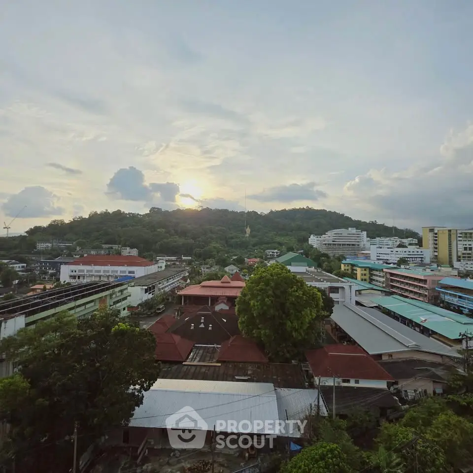 Scenic cityscape view with lush greenery and distant hills at sunset.