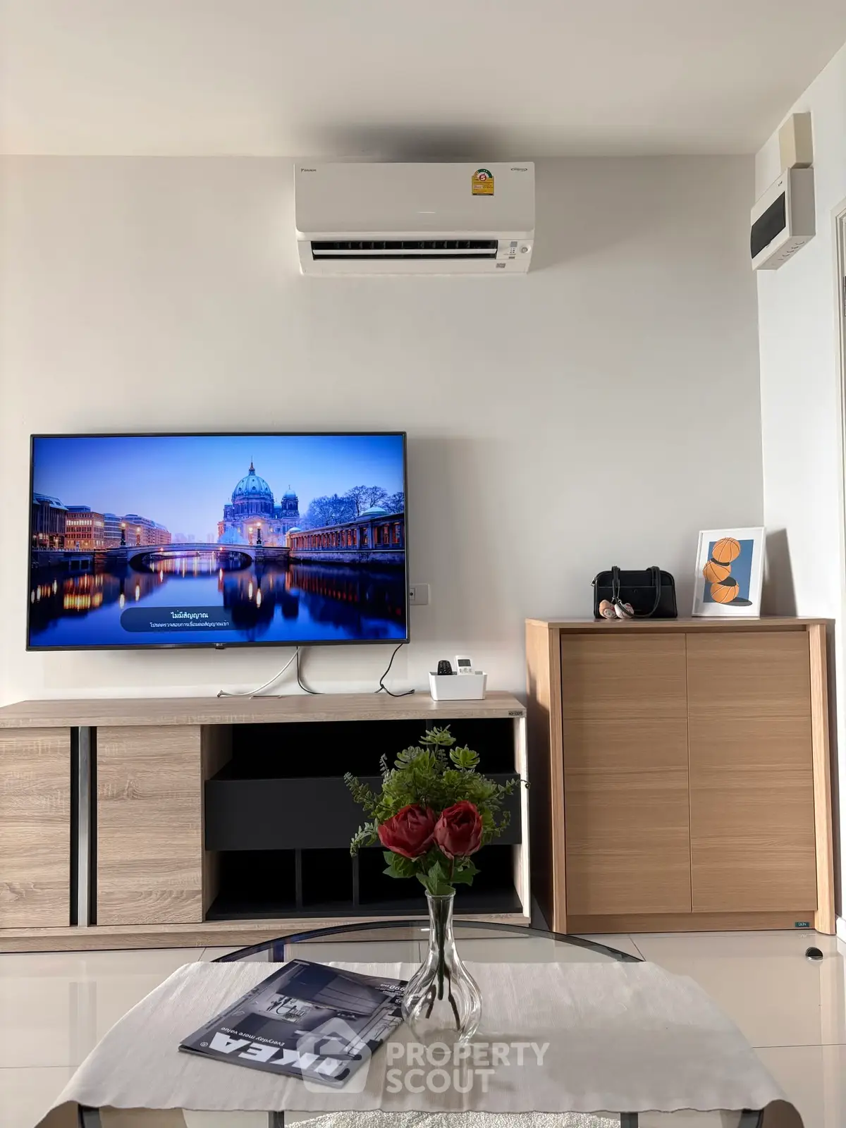 Modern living room with sleek furniture, wall-mounted TV, and air conditioning unit, perfect for comfortable living.