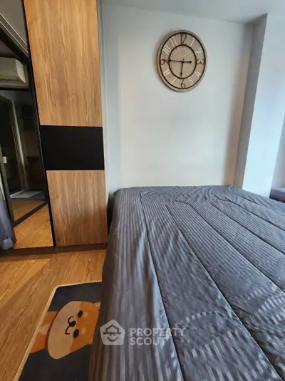Cozy bedroom with stylish clock and wooden wardrobe, featuring a playful rug for a charming touch.