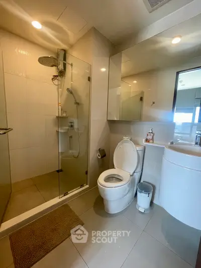 Modern bathroom with glass shower and sleek fixtures in contemporary apartment.