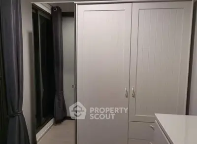 Modern bedroom with sleek wardrobe and large window with elegant curtains.