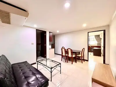 Spacious living room with modern furniture and dining area in a well-lit apartment.