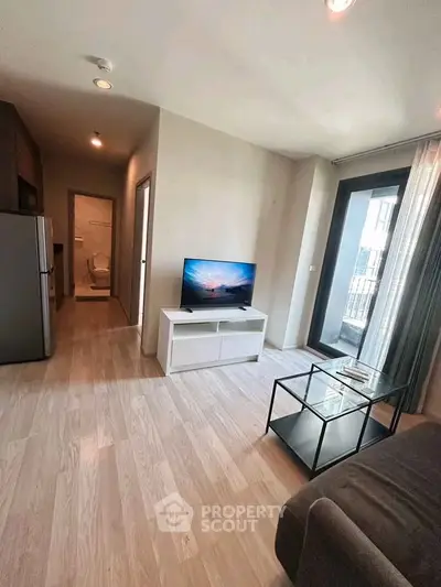 Modern living room with sleek TV setup and balcony access in a stylish apartment.