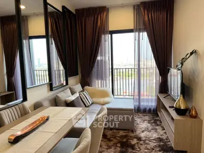 Stylish living room with modern decor, plush rug, and city view through large windows.