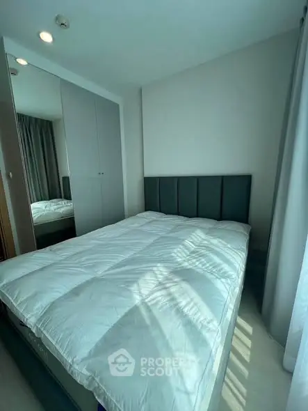 Cozy bedroom with modern decor and ample natural light, featuring a comfortable bed and sleek wardrobe.