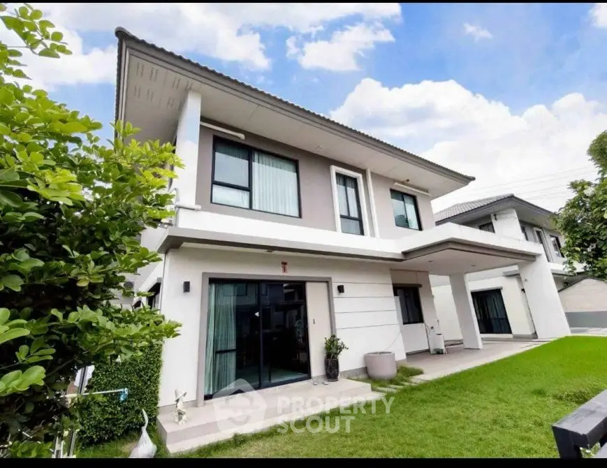 Modern two-story house with lush green lawn and contemporary design.