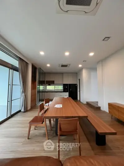 Spacious modern dining area with wooden table and chairs, large windows, and sleek design.