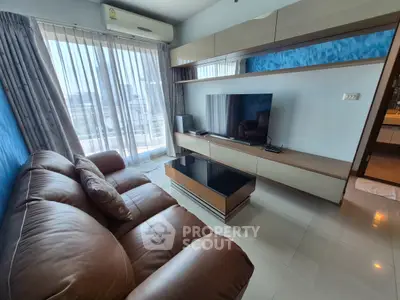 Modern living room with leather sofa, sleek TV unit, and large windows offering city views.