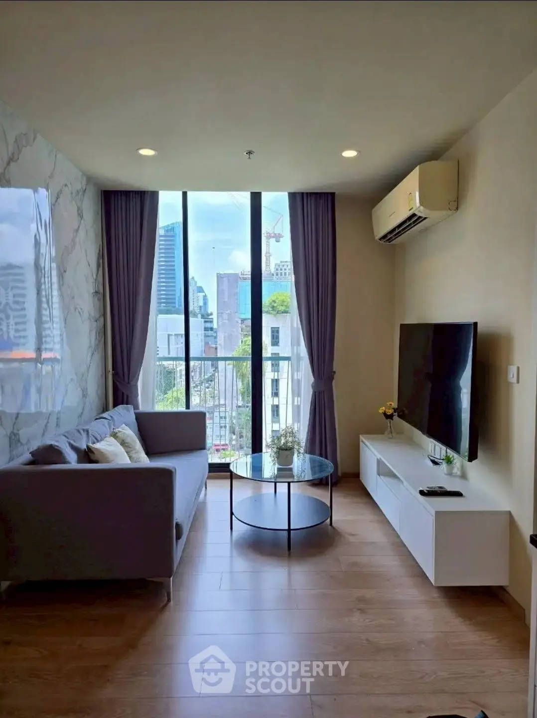 Modern living room with city view, featuring sleek furniture and large windows.