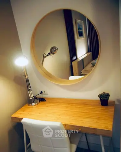Cozy study nook with wooden desk, modern lamp, and round mirror reflecting stylish decor.
