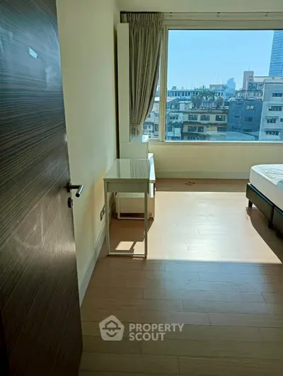 Bright bedroom with large window offering city view and modern furnishings.