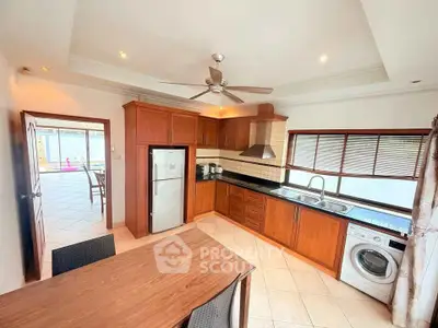 Spacious kitchen with wooden cabinets, modern appliances, and dining area in a bright home.