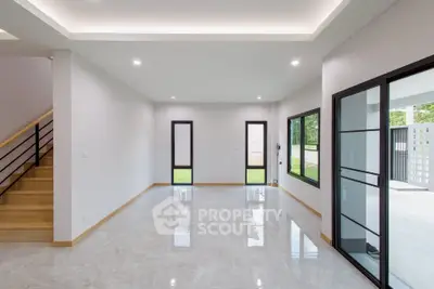 Spacious modern living room with large windows and sleek staircase