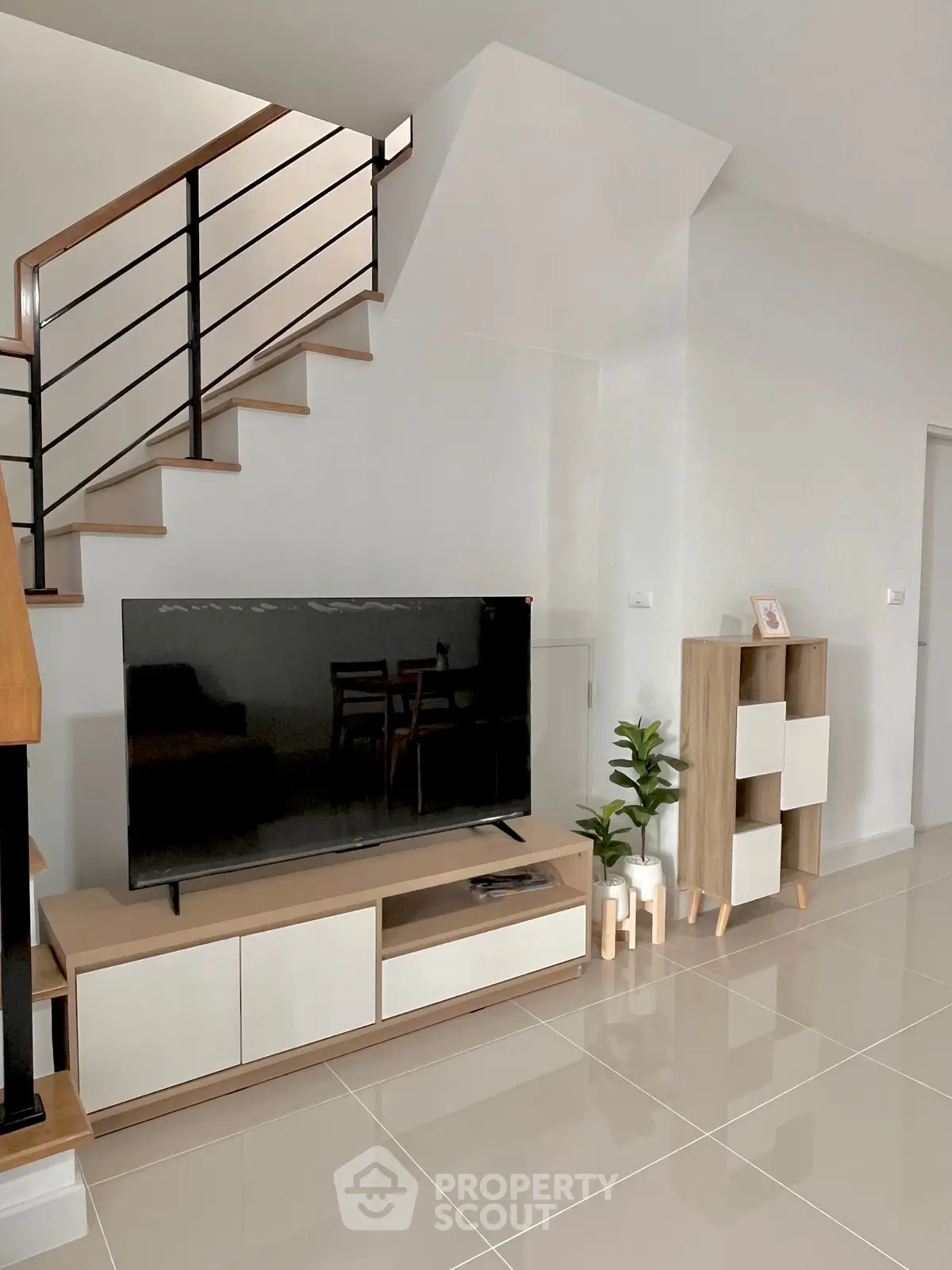 Modern living room with sleek staircase and stylish TV unit, perfect for contemporary living.
