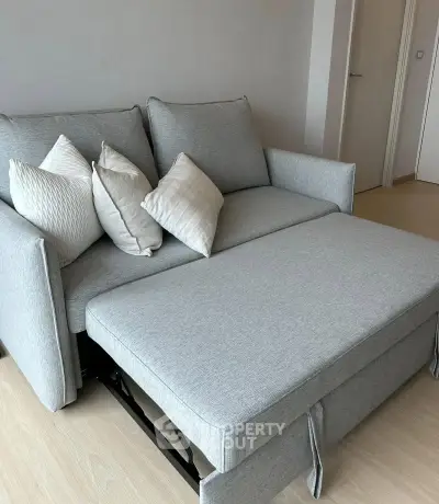 Modern living room with stylish gray sofa bed and decorative pillows.