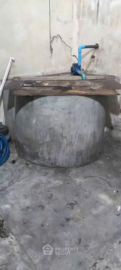 Industrial-style storage area with concrete tank and exposed piping