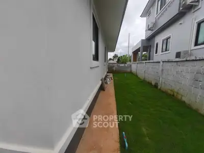 Side view of modern house with green lawn and concrete wall