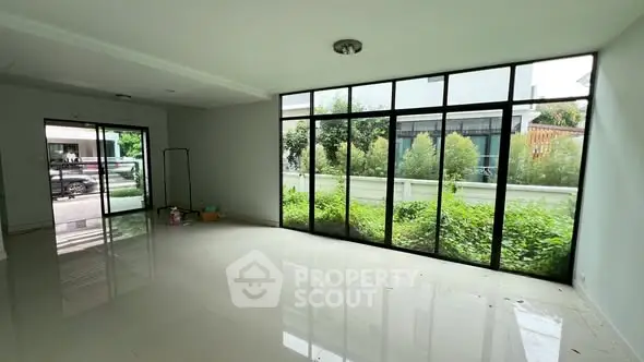 Spacious living room with large windows offering lush garden views, perfect for natural light lovers.